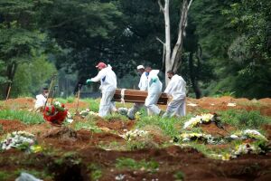 Coveiros com trajes de proteção carregam caixão de mulher que morreu de Covid-19, no cemitério de Vila Formosa, em São Paulo