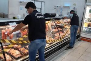 Açougueiros mexiam em carnes em meio a cimento e sujeira
