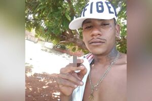 Na imagem, rapaz segura cigarro, possivelmente de entorpecente (imagem borrada em prol da política anti-drogas)