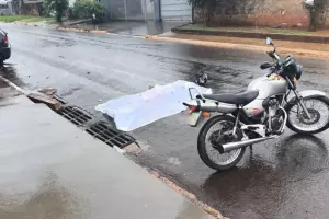 Corpo coberto com lençol ao lado de motocicleta