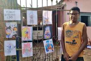 O menino Kaique vende desenhos em frente de casa