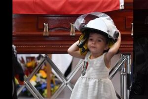 Filha de bombeiro morto em incêndio comove ao usar capacete do pai em velório