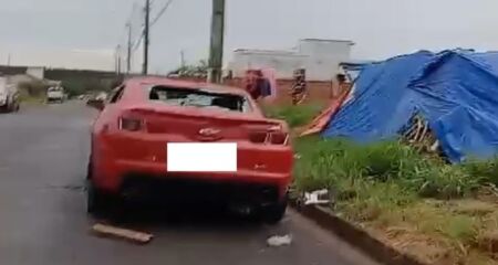 O Camaro, de cor vermelha, estava estacionado em frente a um acampamento
