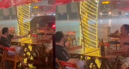 Em clima natalino, amigos brindam enquanto tomam uma gelada durante chuva forte no Centro