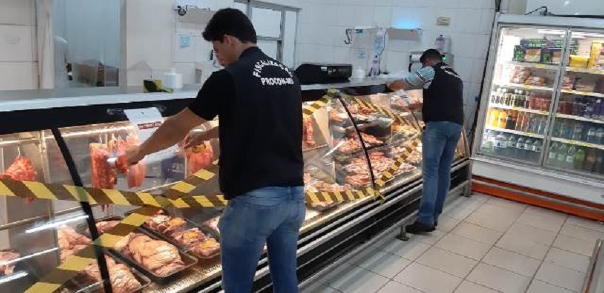 Açougueiros mexiam em carnes em meio a cimento e sujeira